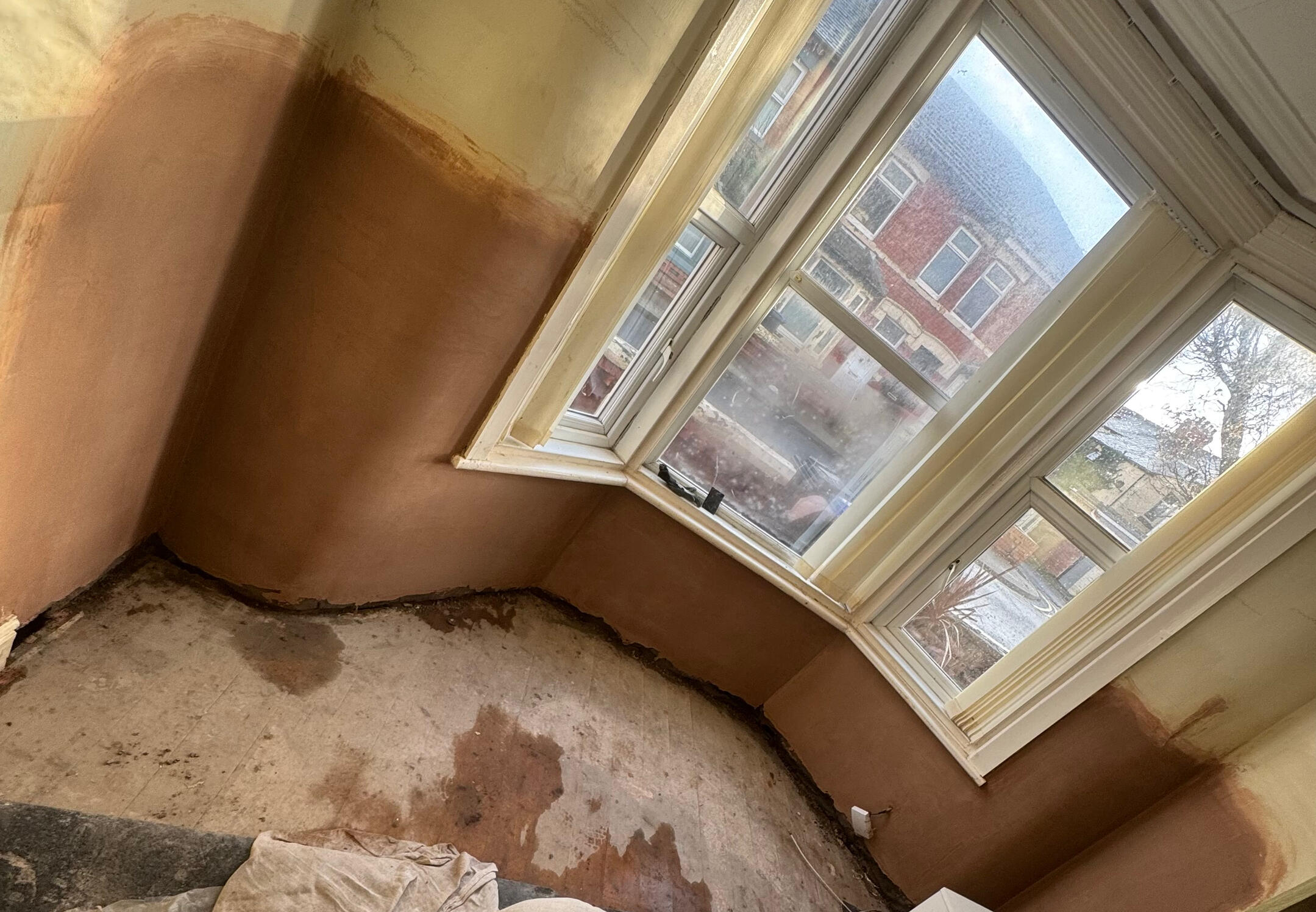 Fresh plaster around the lower walls of a bay window during remedial work
